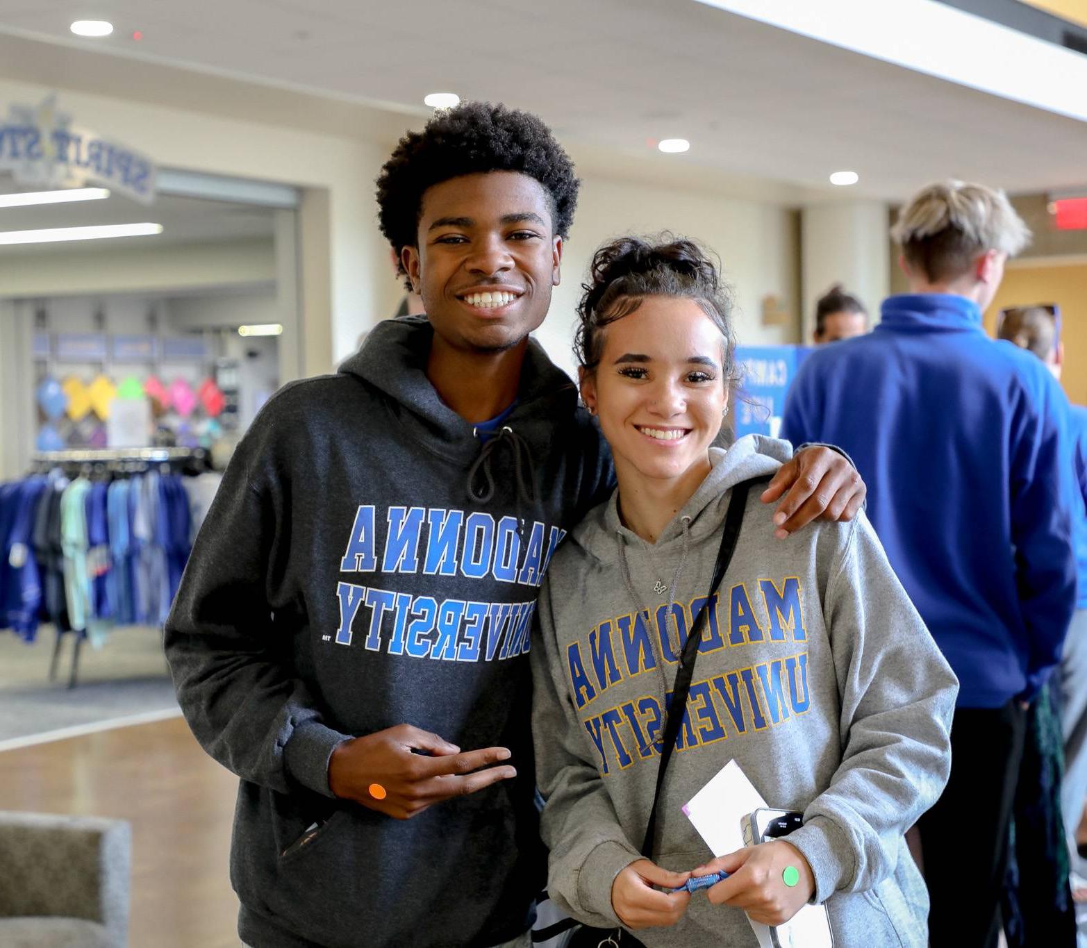 Two students smiling standing in front of the spirit store in the Franciscan Center